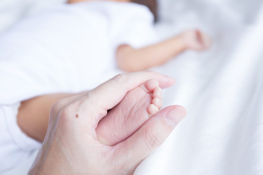 Asian infant baby foot held in parents hands