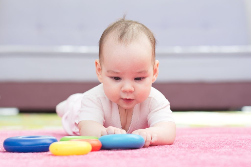 Sweet Baby Crawling And Playing With Toys On Carpet
